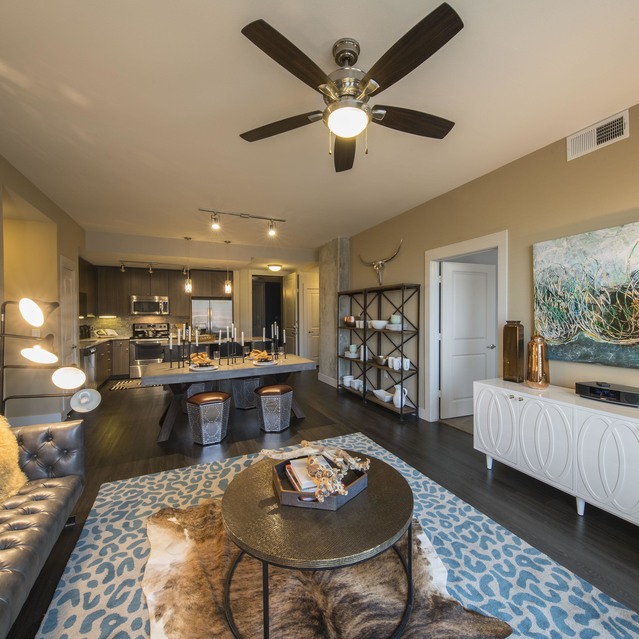 The Arcadian - Living Room with a Ceiling Fan, a Stylish Area Rug, and a Decorative Wall Piece