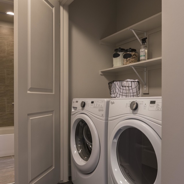 The Arcadian - Small Laundry Closet Featuring a Stacked Washer and Dryer with Shelves Above