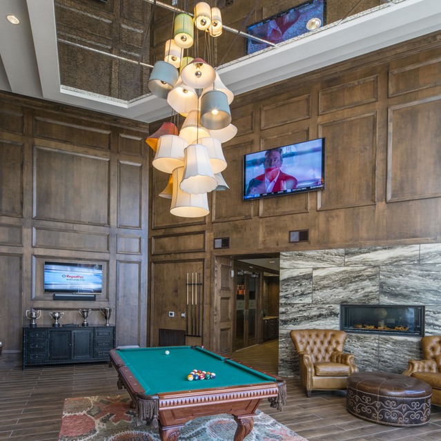 The Arcadian - Elegant Lounge Featuring a Pool Table and a Wall-Mounted TV Against a Wooden Wall