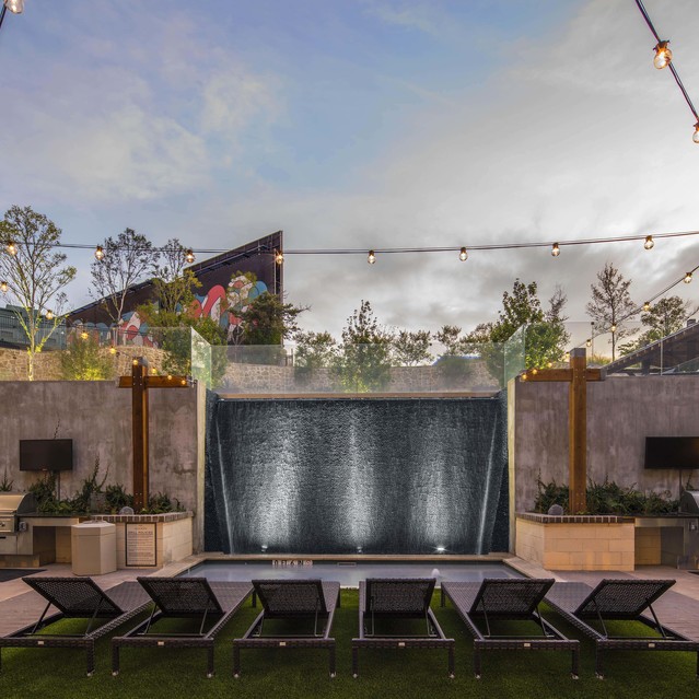 The Arcadian - An Outdoor Space Featuring Lounge Chairs and String Lights, Surrounded By Greenery and Modern Architecture