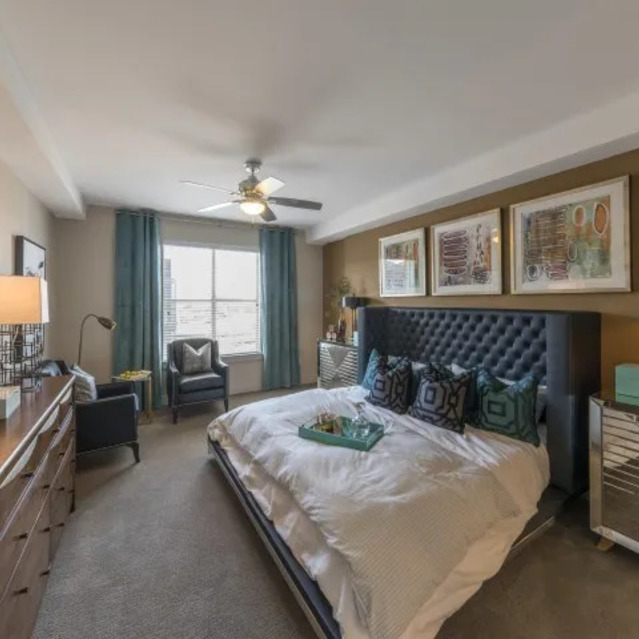 The Arcadian - Modern Bedroom Featuring a Queen Bed with Decorative Pillows, a Wooden Dresser, and a Side Table