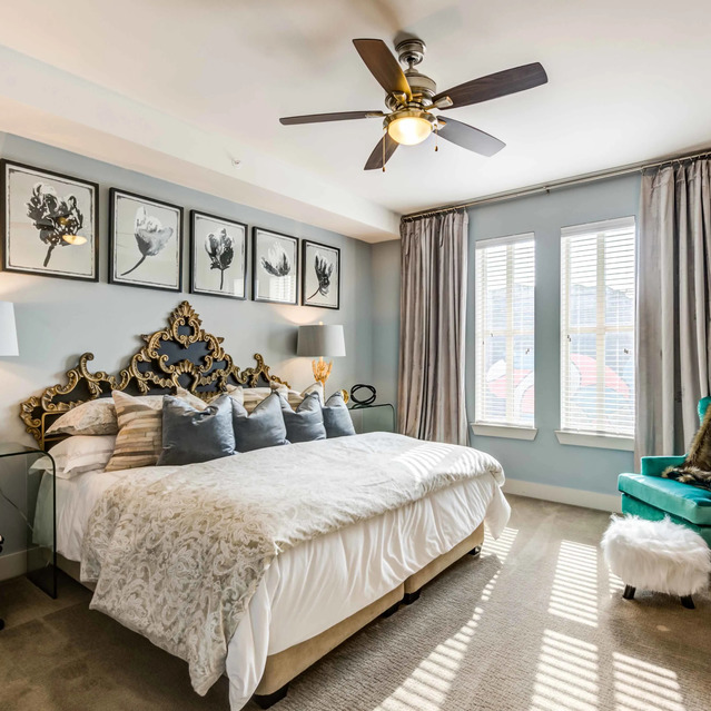 The Arcadian - Bright Bedroom Featuring a Large Bed with Framed Art and a Teal Armchair
