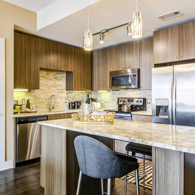 The Arcadian - Kitchen with Wood Cabinets, a Marble Island, and Stainless-Steel Appliances